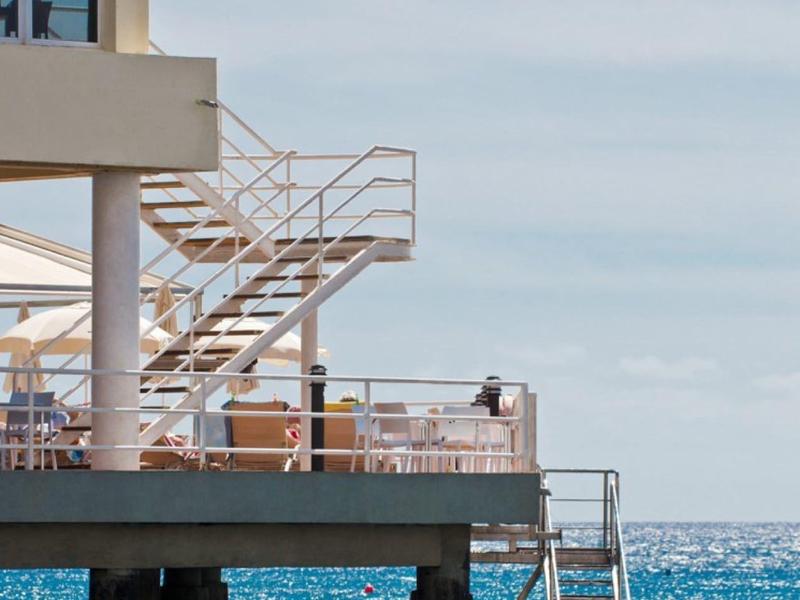 Un molo moderno con scale sopra il mare blu sotto un cielo limpido.