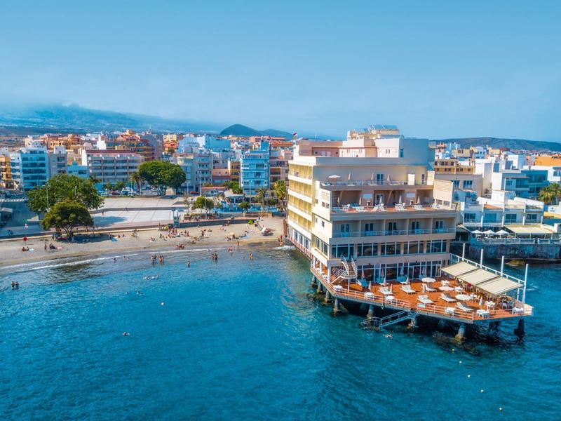 Moderno edificio alberghiero sull'acqua con terrazza affacciata sulla spiaggia e sulla città.