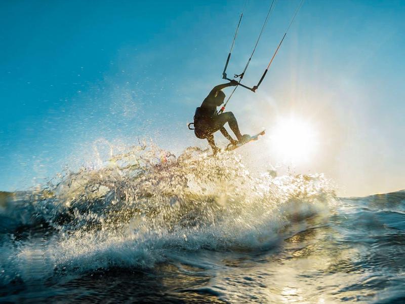 Kitesurfer salta sopra le onde al tramonto sull'oceano.