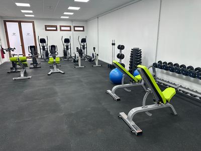 Gimnasio con máquinas de ejercicio, pesas y balón de gimnasia en un hotel moderno.