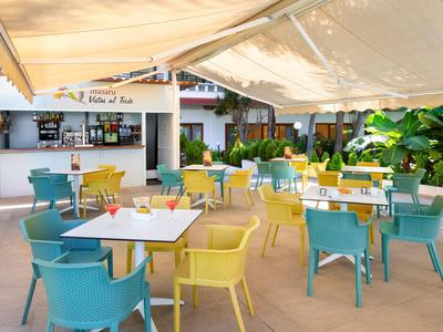 Chaises et tables colorées sous un auvent dans un restaurant en plein air d'hôtel.