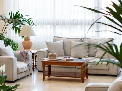 Un salon confortable avec de grandes fenêtres, des plantes et une table en bois.