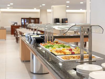 Un espace buffet moderne avec divers plats et des assiettes blanches empilées.