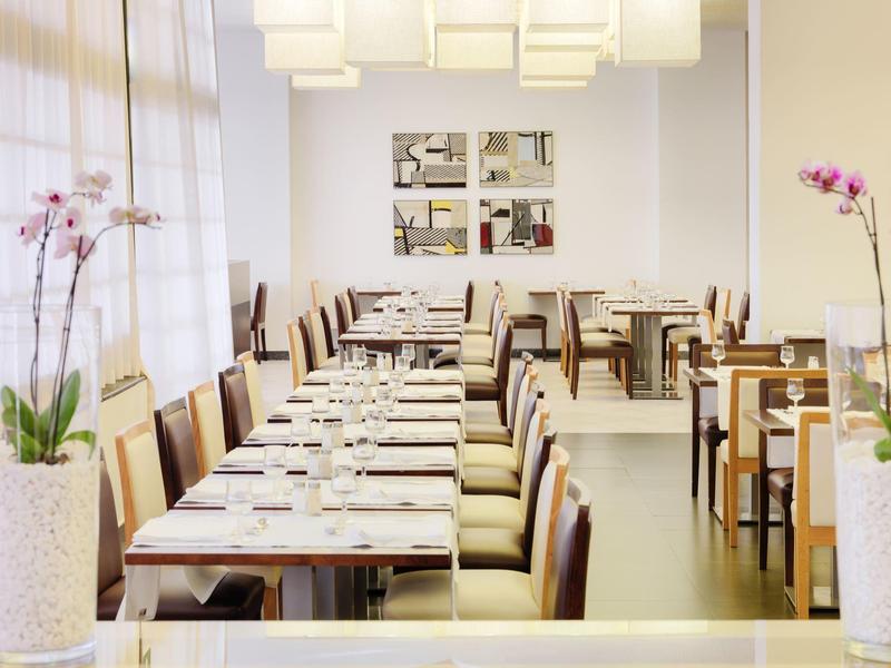 Jasne wnętrze restauracji z długimi stołami, krzesłami i storczykami