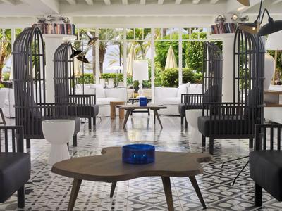 Espace lounge d'hôtel moderne et lumineux avec des sièges uniques en forme de cage noire et des tables en bois et verre.