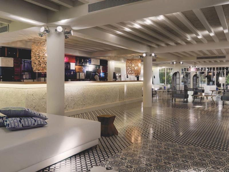 Spacious hotel lobby with modern white seating, patterned floor, and soft lighting