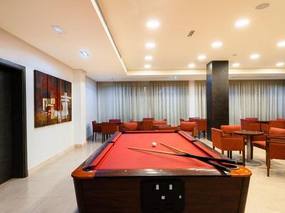 Stylowy pokój gier z czerwonym stołem bilardowym i przytulnymi miejscami do siedzenia w ciepłym świetle.