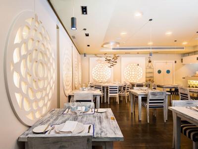 Jasna restauracja z okrągłymi dekoracjami ściennymi i nakrytymi stołami z drewnianymi krzesłami.