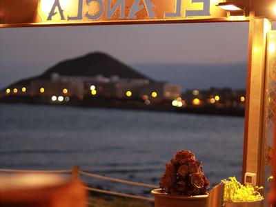 Evening view from a hotel restaurant overlooking water and illuminated mountain.
