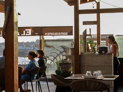 Hotel terrace with seating area, view of the river and urban backdrop.