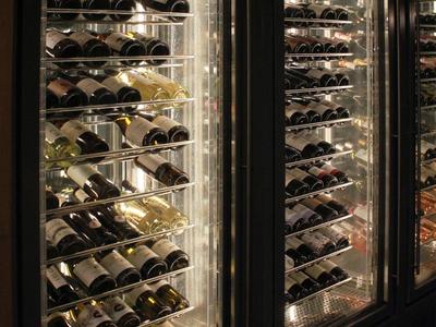 Refrigerated display case with multiple shelves filled with bottles of various wines.