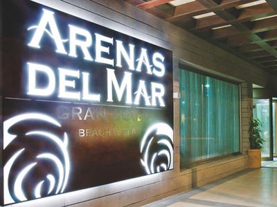Entrée d'hôtel avec panneau illuminé 'Arenas del Mar' et façade en verre moderne.