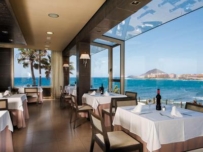 Restaurant élégant avec nappes blanches et vue sur la mer par une journée ensoleillée.