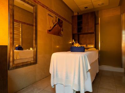 Salle de spa confortable avec table de massage, serviettes et éclairage chaleureux.