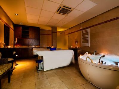 Salle de bien-être moderne avec table de massage et jacuzzi sous un éclairage tamisé