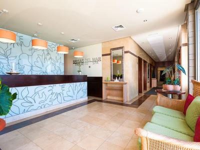 Jasny hol hotelowy z recepcją, miejscem do siedzenia i zielonymi roślinami.