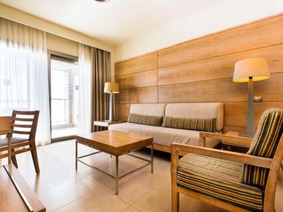 Jasny salon z drewnianymi meblami, sofami i dużym oknem z zasłonami.