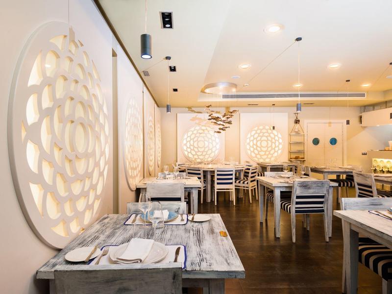 Jasna restauracja z okrągłymi dekoracjami ściennymi i nakrytymi stołami z drewnianymi krzesłami.