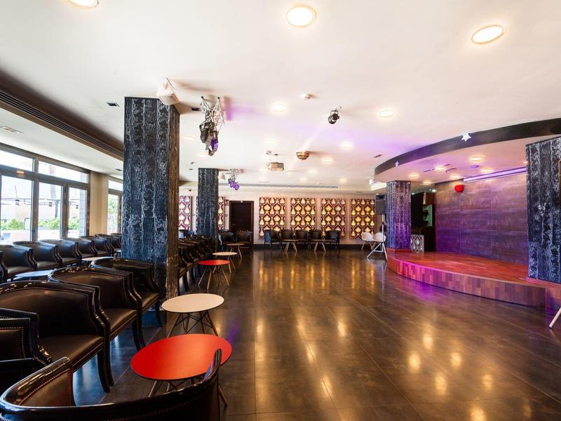 Pusta sala eventowa z sceną, miejscami do siedzenia i drewnianą podłogą w hotelu.