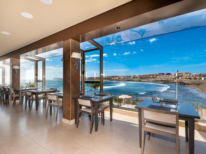 Nowoczesna restauracja z stolikami przy oknie z widokiem na wybrzeże i morze.
