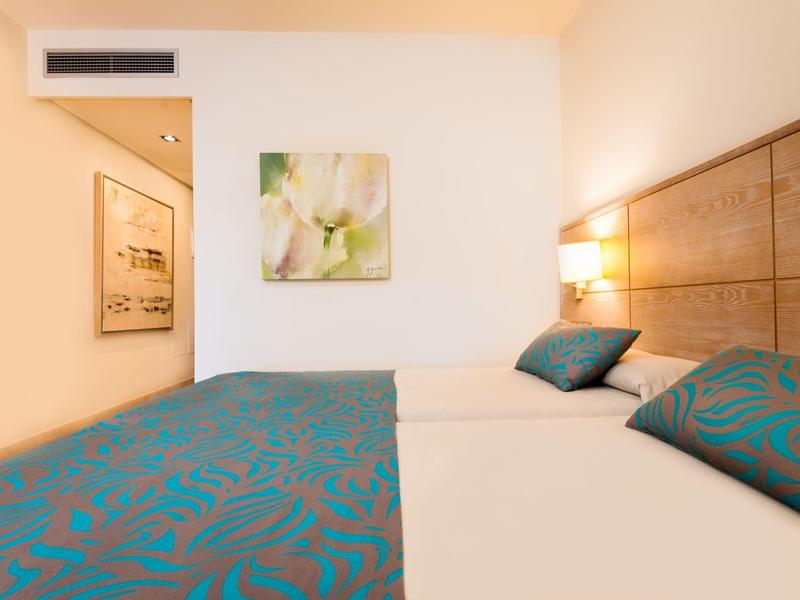 Jasno umeblowany pokój hotelowy z łóżkiem podwójnym i nowoczesnym wystrojem.