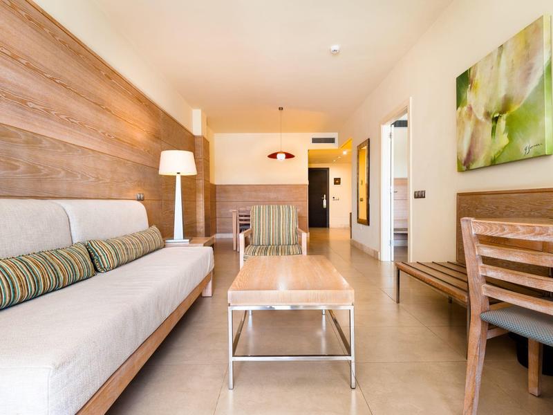 Nowoczesny salon z sofą, stolikiem kawowym i stołem jadalnym w pokoju hotelowym.