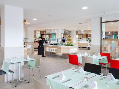 Ristorante di un hotel moderno con tavoli apparecchiati e una persona sullo sfondo.