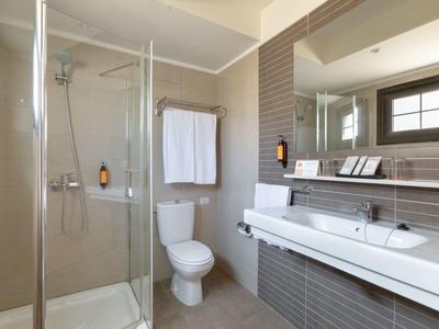 Bagno moderno con doccia, WC e lavabo in tonalità neutre.