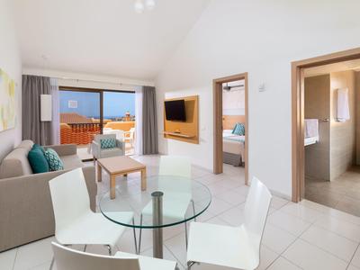 Soggiorno luminoso con tavolo da pranzo in vetro e divano, vista su balcone con vista mare.