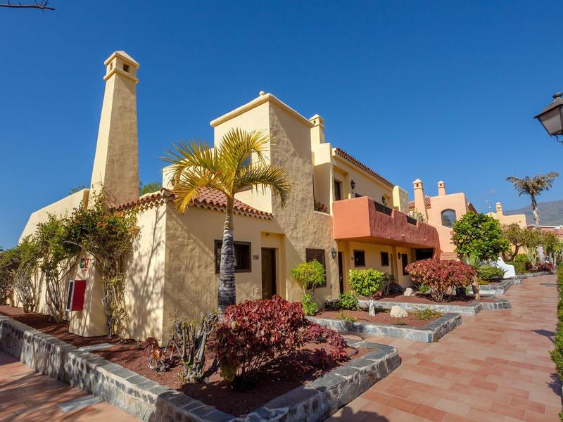 Complesso alberghiero con edifici gialli, palme e cielo azzurro limpido.