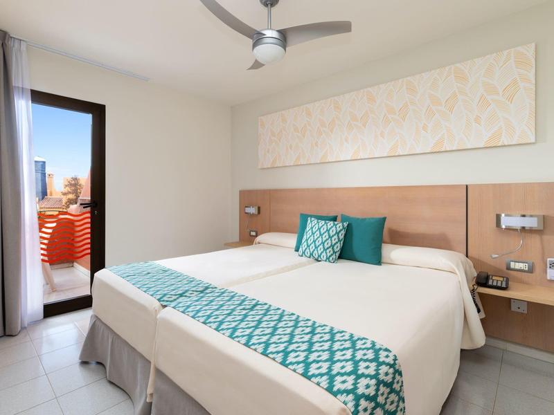 Camera d'hotel moderna con letto matrimoniale, terrazza e vista sulla città di giorno.