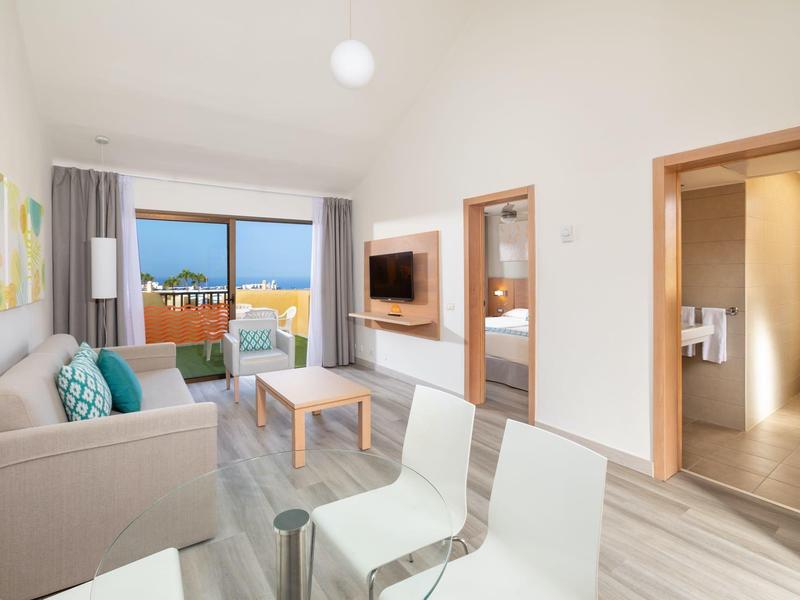 Soggiorno moderno con divano, sedie e balcone con vista sul mare.