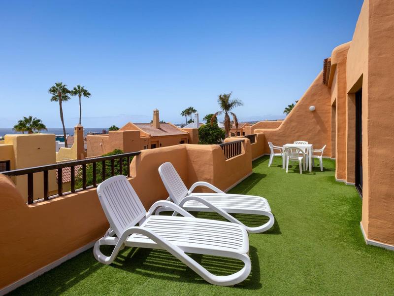 Terrazza con lettini con vista su palme e mare in una giornata di sole