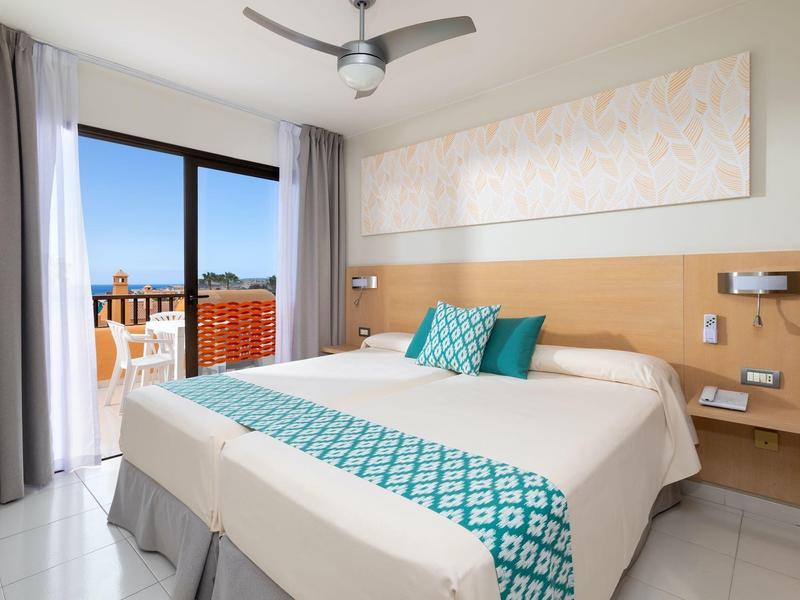 Camera d'hotel luminosa con letto matrimoniale e balcone con vista mare.