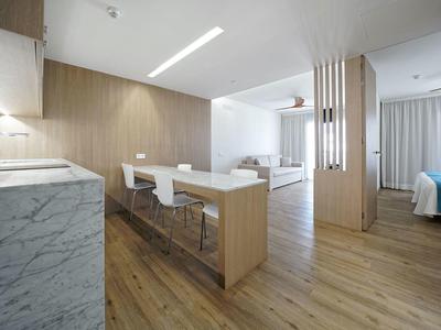 Moderne offene Küche mit Holzdekor, weißen Barhockern und Holzboden in hellem, minimalistischem Stil.