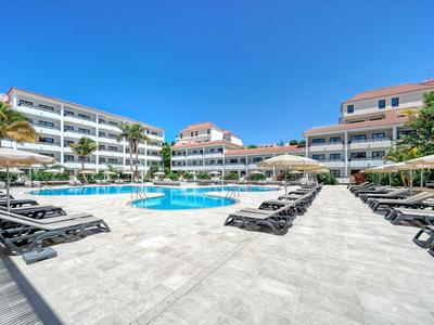 Großer Außenpool mit Liegen und Sonnenschirmen vor mehrstöckigen Hotelgebäuden unter klarem Himmel.