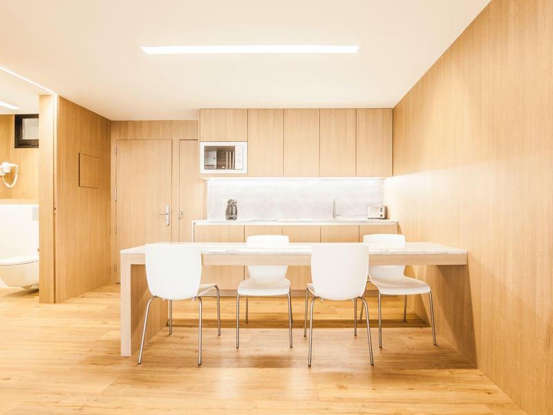 Moderner heller Konferenzraum mit Holzvertäfelung, großem Tisch und weißen Stühlen.