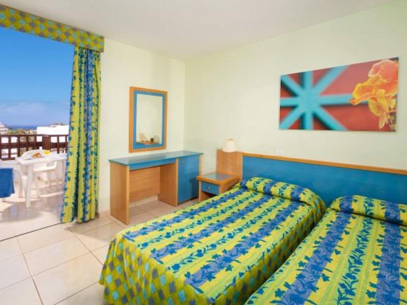 Camera d'hotel luminosa con due letti singoli e balcone con vista sul mare.