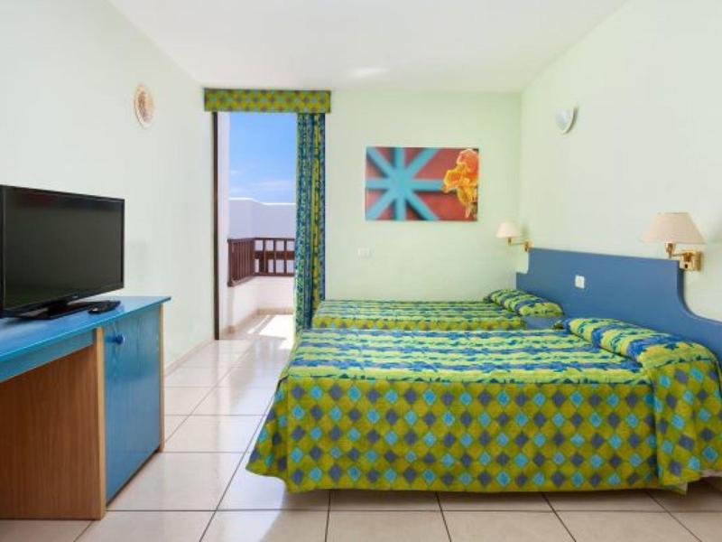 Una semplice camera d'hotel con letto matrimoniale, TV e accesso a un balcone.