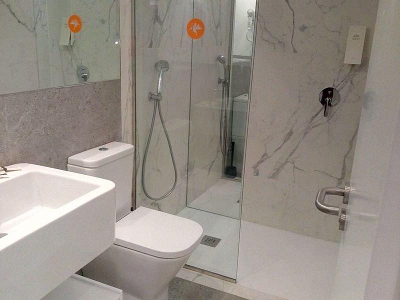 Bagno moderno con doccia, wc, lavabo e grande specchio.