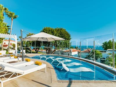 Obszar basenu z leżakami i parasolami pod niebieskim niebem w miejscu wakacyjnym.