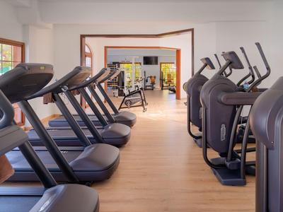 Moderne Fitnessräume mit Laufbändern und Crosstrainern in hellem, geräumigem Raum.