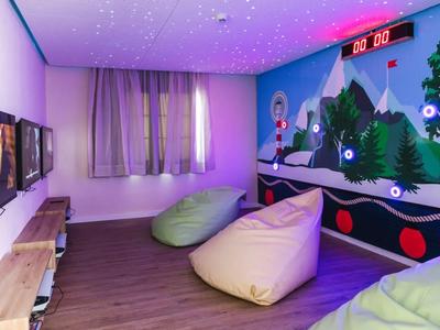 Kolorowy pokój zabaw z workami sako, grami na ścianie i gwiaździstym sufitem dla dzieci w hotelu.