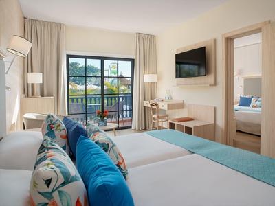 Jasny pokój hotelowy z łóżkiem podwójnym, balkonem i nowoczesnym wystrojem.