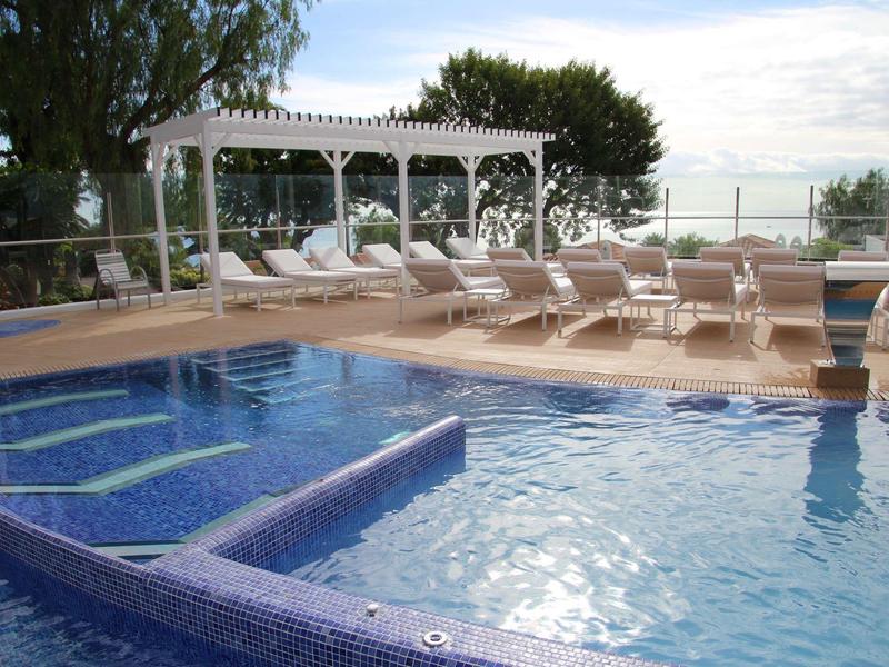 Nowoczesny basen na zewnątrz z leżakami i widokiem na morze