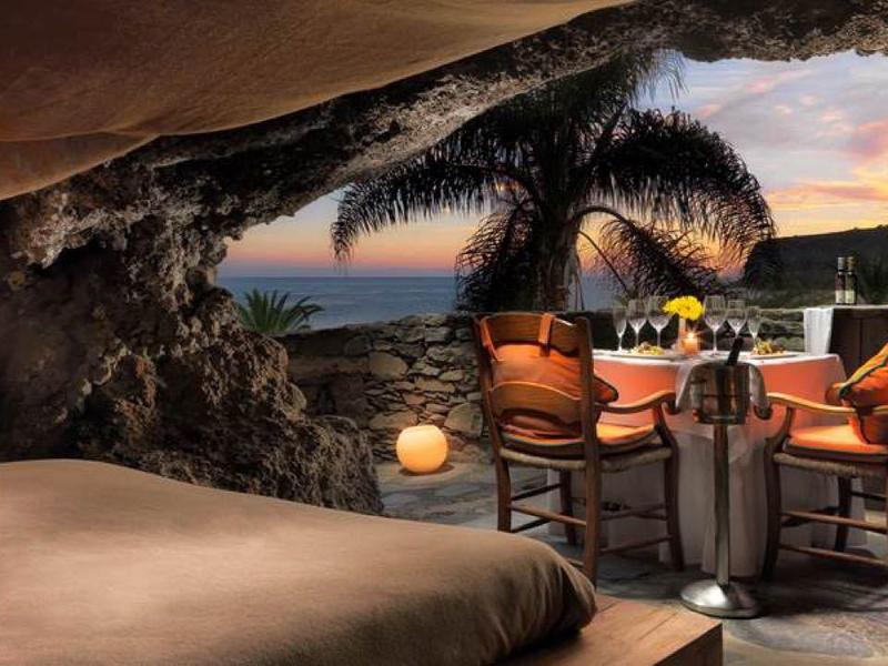 Przytulny bar na świeżym powietrzu z widokiem na morze o zachodzie słońca i roślinnością tropikalną.