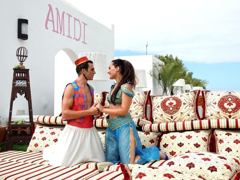 Para w tradycyjnych strojach siedzi i rozmawia na udekorowanym zewnętrznym miejscu do siedzenia.