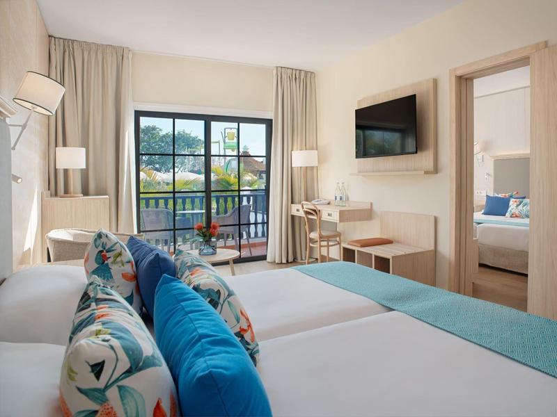 Jasny pokój hotelowy z łóżkiem podwójnym, balkonem i nowoczesnym wystrojem.