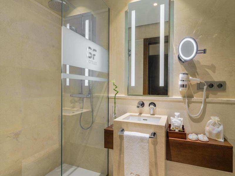 Moderne badkamer met douche, verlichte spiegel en wastafel met handdoek.