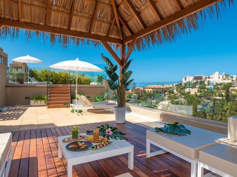 Overdekt terras met comfortabele zitplaatsen en uitzicht op een zonnig, groen landschap.